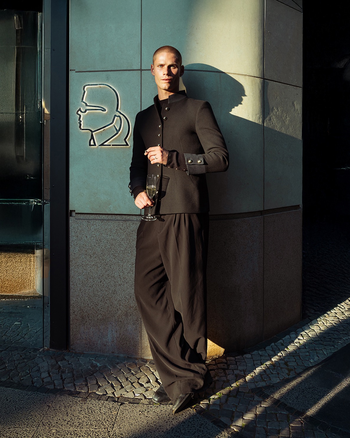 Model Benjamin mit Champagnerglas vor Lagerfeld Silhouette in Berlin
